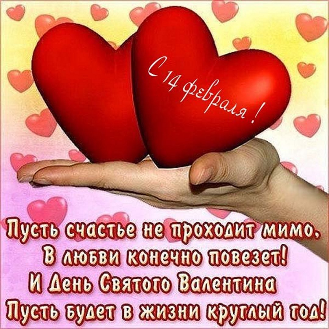 Рука держит два красных сердца на фоне розовых сердечек, с пожеланиями на День святого Валентина на русском языке.