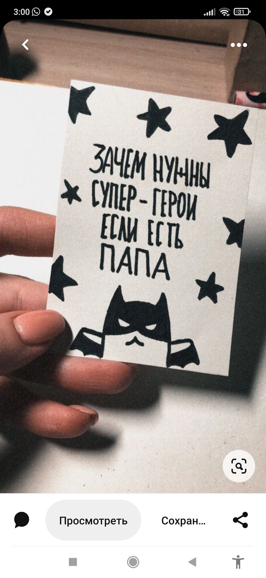 Рука держит открытку с написанным текстом Зачем нужны супер герои если есть папа и изображением Batman, украшенную звёздами.