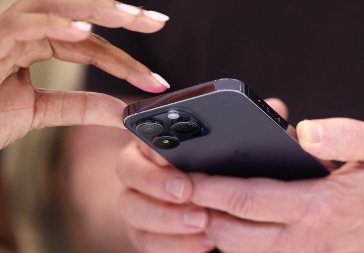 Женщина использует черный смартфон с тройной камерой