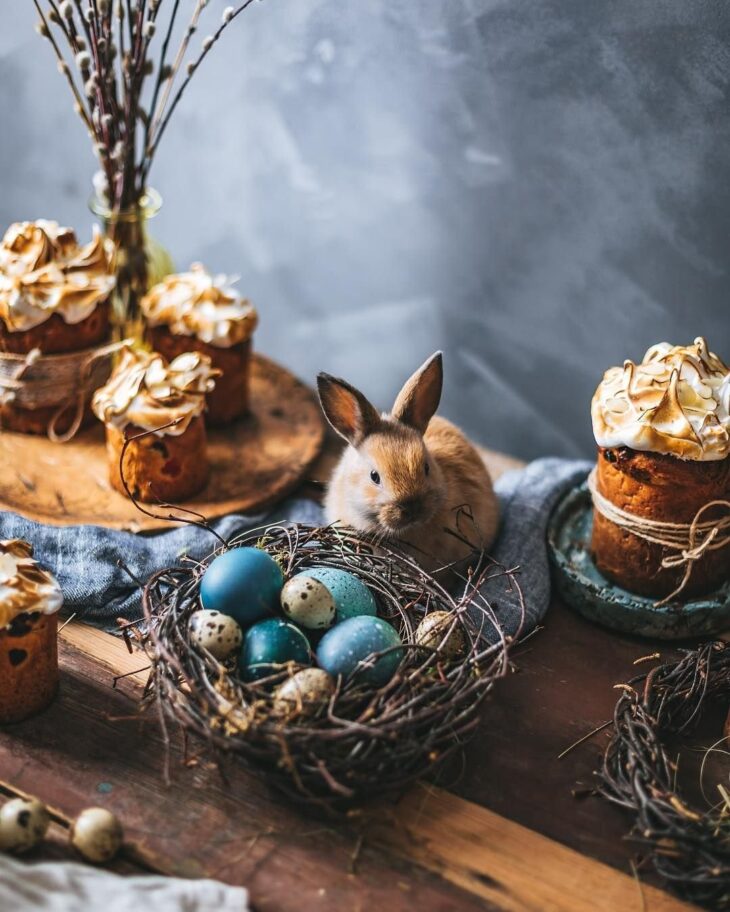 Кролик рядом с пасхальным куличом и гнездом с яйцами