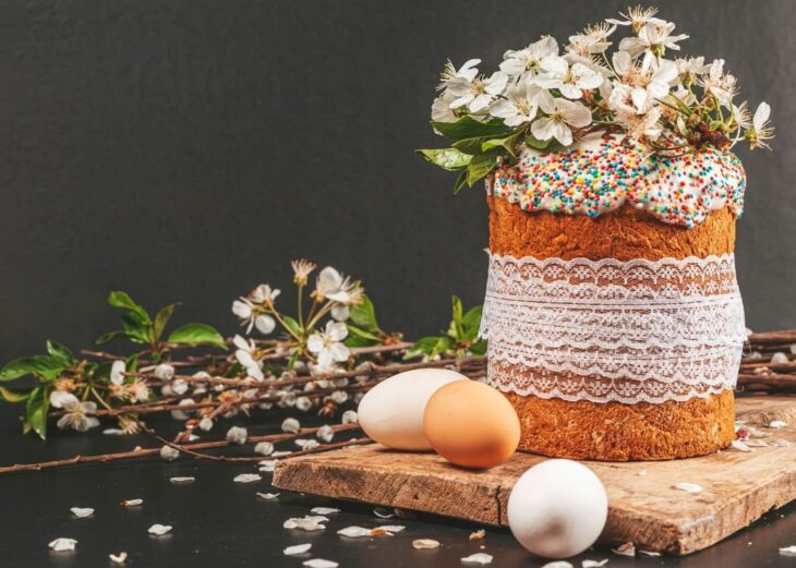 Пасхальный кулич с цветами на фоне весенних веток